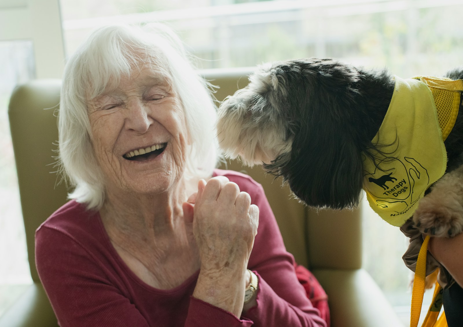 A patient smiling with a therapy dog